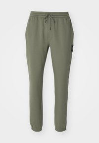 Olivegröna joggarbyxor i mjukt material, med en elastisk midja med snodd och ankelmanschetter, samt detaljer med sidofickor.