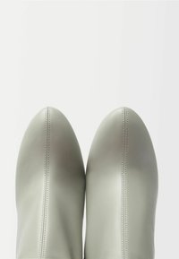 Szare skórzane botki za kostkę o gładkiej fakturze, z ostro zakończonymi noskami i kontrastującymi szwami z przodu. Prosty design skoncentrowany na kształcie.