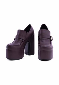 Scarpe platform in pelle marrone con tacco a blocco alto, punta arrotondata e una larga fascia orizzontale con un accento di fibbia metallica.