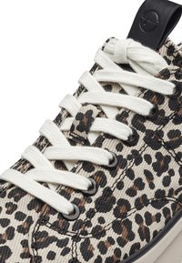 Baskets à imprimé léopard avec une tige en toile beige, des accents noirs, des lacets blancs et des œillets métalliques. Dotées d'un tissu texturé et d'une semelle lisse.