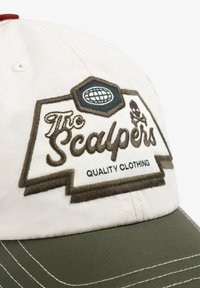 Gorra de béisbol con una parte superior color crema y visera verde. Presenta un logotipo bordado en marrón y el texto "The Scalpers Quality Clothing". Detalles de costura texturizada.