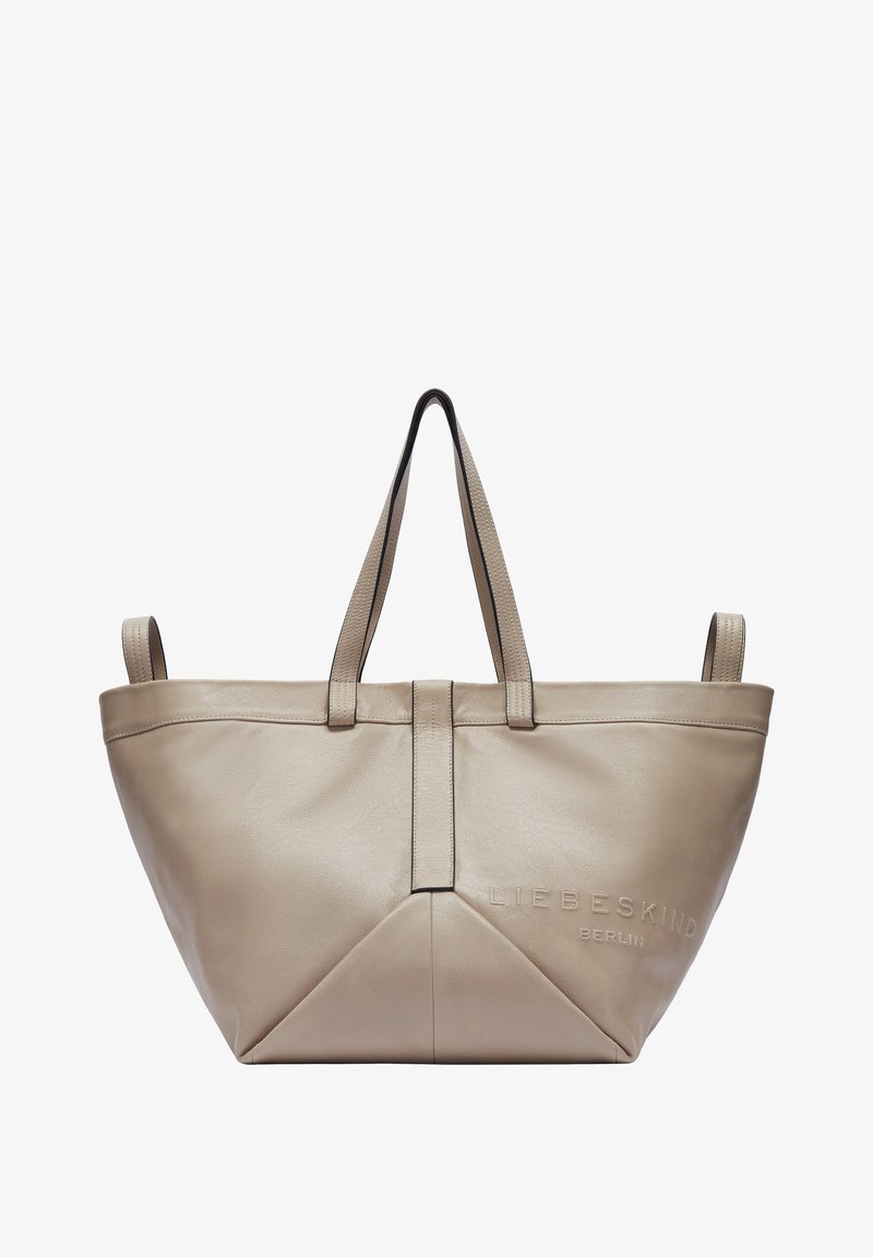 Sac fourre-tout en cuir beige au design structuré, avec deux poignées, un détail de logo et une couture triangulaire en bas. Texture lisse.