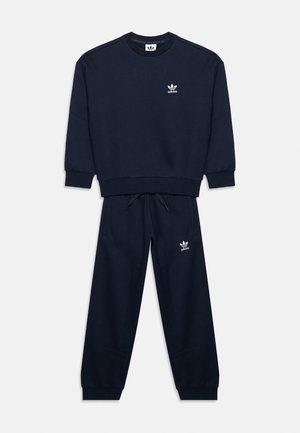 Σκούρο μπλε φόρμα Adidas με μακρυμάνικο φούτερ και τζόγκερ παντελόνι που ταιριάζει, κάθε ένα με μικρό λευκό λογότυπο Adidas στο στήθος και στο μηρό.