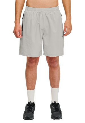 Lys grå sportshorts med elastisk talje, sidelommer og struktureret finish, parret med sorte sko og hvide sokker.