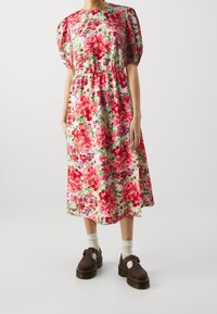 Kukkakuvioinen midi-mekko puff-hihalla, jossa on punaisia ja vaaleanpunaisia ruusuja vaalealla taustalla. Sileä kangas, vyötäröltä kireä ja rento istuvuus.