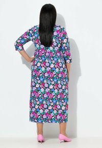 Květinové maxi šaty s tříčtvrtečními rukávy. Vzor s vícebarevnými květy na černém pozadí. Růžové boty na vysokém podpatku.