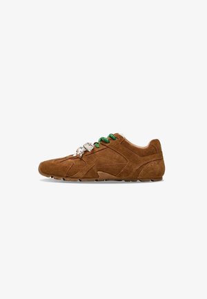 Sneaker casual in suede marrone con lacci verdi e bianchi, suola testurizzata e design con pannelli cuciti, mostrato in profilo laterale.