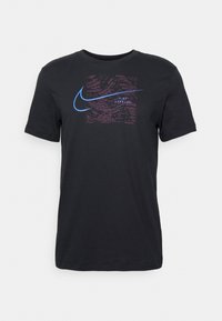 Camiseta negra de manga corta, con un diseño gráfico texturizado que incluye acentos en rosa y azul, y el logo de Nike centrado en el pecho.