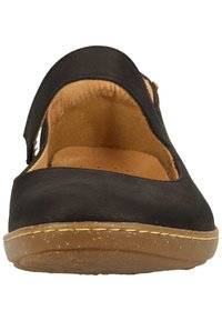 Chaussures Mary Jane en cuir noir avec un design découp é, une sangle ajustable et une semelle en caoutchouc beige avec une légère texture.
