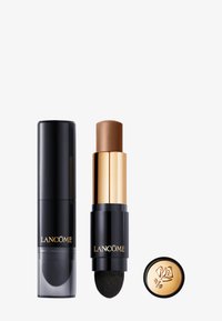 Producto de maquillaje de Lancôme con doble punta; tubo negro con acentos dorados, un extremo presenta un lápiz bronceador, mientras que el otro tiene un cepillo aplicador.