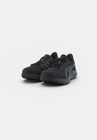 Baskets de sport noires avec un dessus en maille texturée, un système de laçage et une semelle en caoutchouc avec un léger talon. Design élégant avec des accents minimalistes.