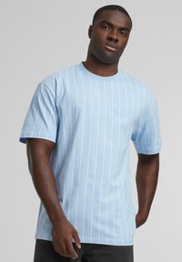 Ljust blå bomull T-shirt med vita vertikala ränder och korta ärmar, med en liten broderad logotyp på bröstet.