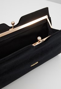 Clutch in tessuto nero con una cornice metallica dorata, caratterizzata da un interno testurizzato e un dettaglio di chiusura abbinato. Logo posizionato sulla parte anteriore.