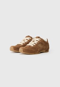 Brown suede sneakers with cream laces, a textured body, rubber sole, and mesh panel detailing. Rounded toe and padded collar.