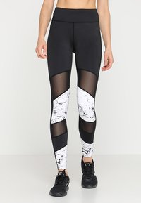 Leggings sportivi in bianco e nero con un motivo marmorizzato, pannelli in rete, vita alta e una texture liscia. Progettati per l'abbigliamento attivo.