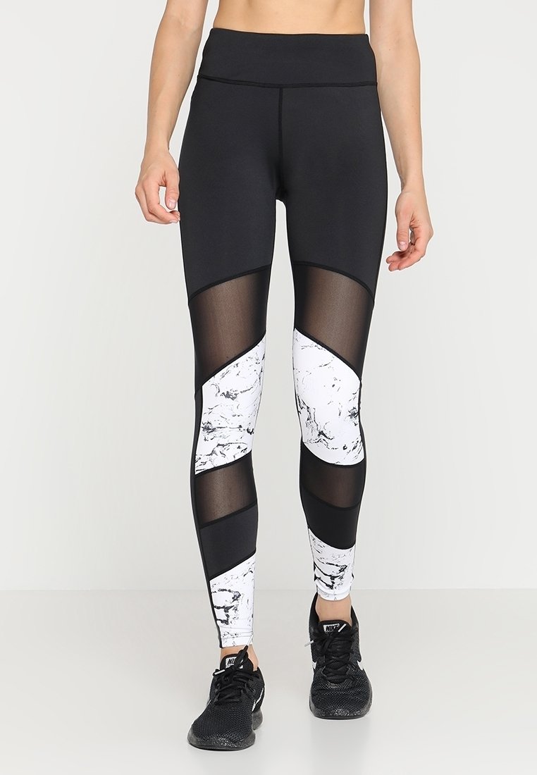 Leggings sportivi in bianco e nero con un motivo marmorizzato, pannelli in rete, vita alta e una texture liscia. Progettati per l'abbigliamento attivo.