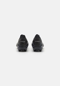 Black football boots with a sleek design, rubber studs, and textured detailing on the upper. Branding on the heels reads "MORELIA" and "NEO."