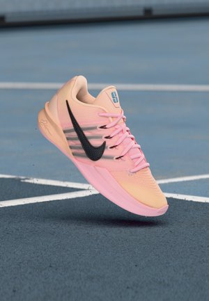 Športni čevelj Nike v svetlo roza in breskovi barvi, z črnimi poudarki, zgornjim delom iz teksturirane mreže in ukrivljeno zasnovo podplata s kontrastnimi vezalkami.