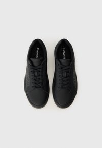 Adidași negri realizati din materiale netede și texturate, cu un model geometric pe laterale, vârf rotund și sistem de șiret.