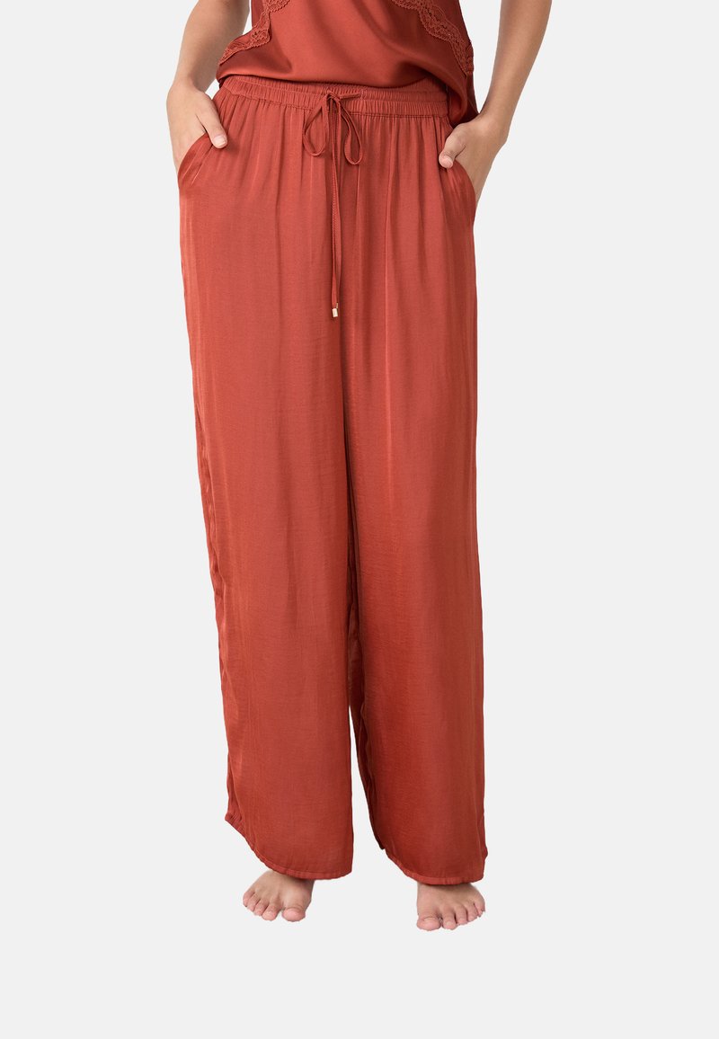 Losse, roestkleurige broek met een elastische tailleband, trekkoordsluiting en zijzakken. Zacht, lichtgewicht stof met een gladde textuur.