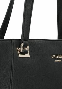 Borsa nera realizzata in materiale testurizzato, con chiusura metallica dorata e marchio. Due spallacci per una maggiore funzionalità.