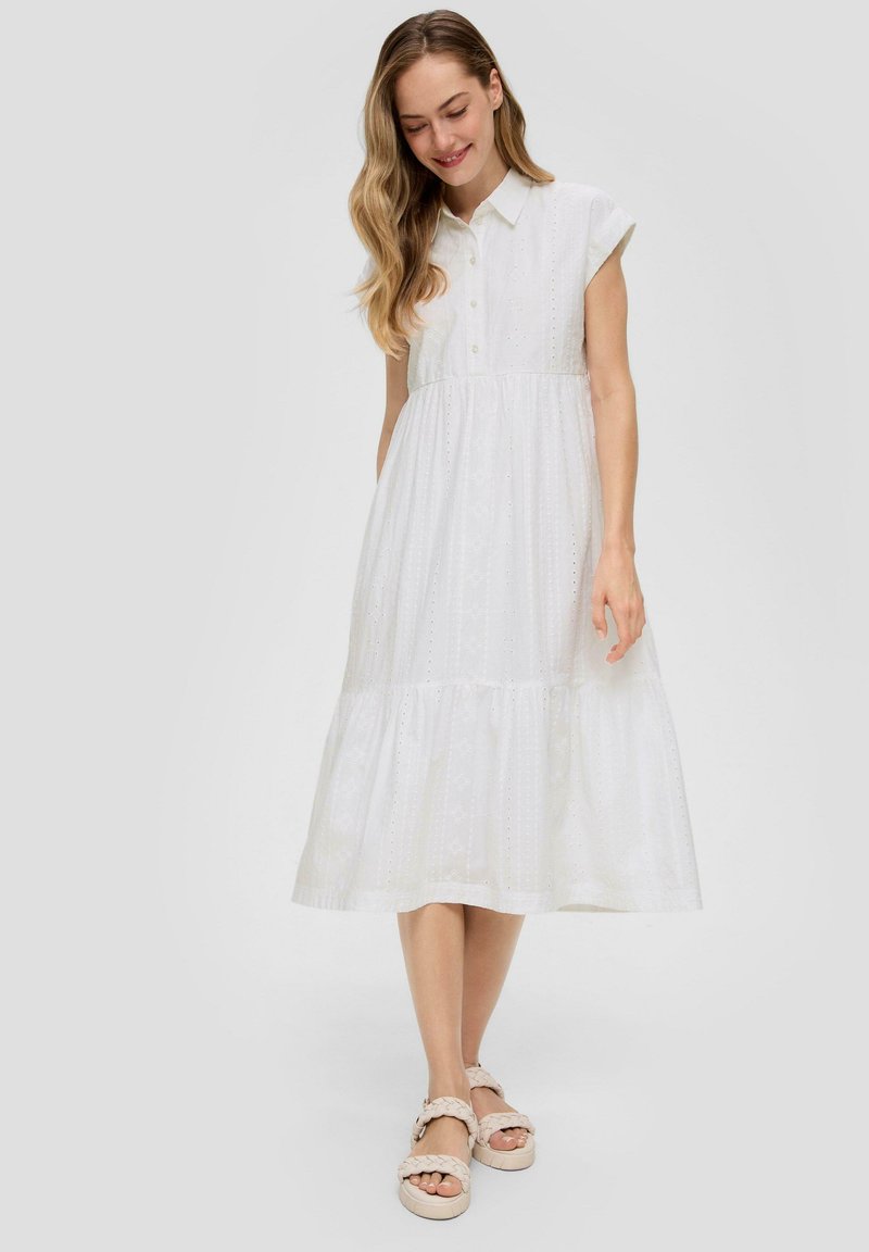 Witte katoenen midi-jurk met een kraag, korte mouwen, knoopdetails en een gelaagde rok met subtiele textuur en perforaties.