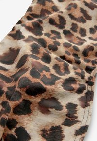 Tessuto con stampa leopardata che presenta una miscela di toni beige, marrone e nero. Texture morbida con dimensioni delle macchie variabili e design fluido e armonioso.