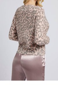 Sweter w panterkę w jasnoróżowym i szarym kolorze, o miękkiej fakturze, okrągłym dekolcie i prążkowanym wykończeniu. W komplecie z błyszczącymi, srebrnymi spodniami.