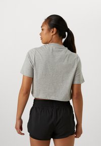 Kuttet grå t-skjorte med kort erme, parret med svarte treningsshorts med elastisk liv og sidelommer.