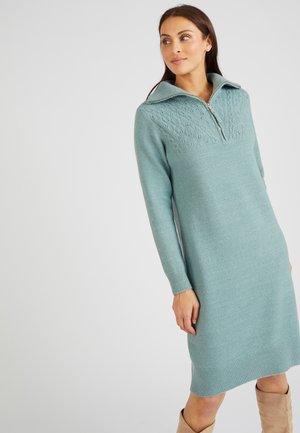 Abito a maglia azzurro chiaro con collo a zip, caratterizzato da un motivo testurizzato sul giromanica e maniche lunghe, che termina a metà polpaccio con dettagli a coste.