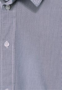 Košile s krátkým rukávem na knoflíky s vertikálním pruhem světle modré a bílé barvy, vybavená standardním límcem a plastovými knoflíky.