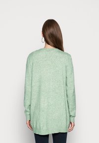 Světle zelený pletený svetr s volným střihem, kulatým výstřihem a žebrovanými manžetami a spodním lemem, který se vyznačuje měkkou texturou.