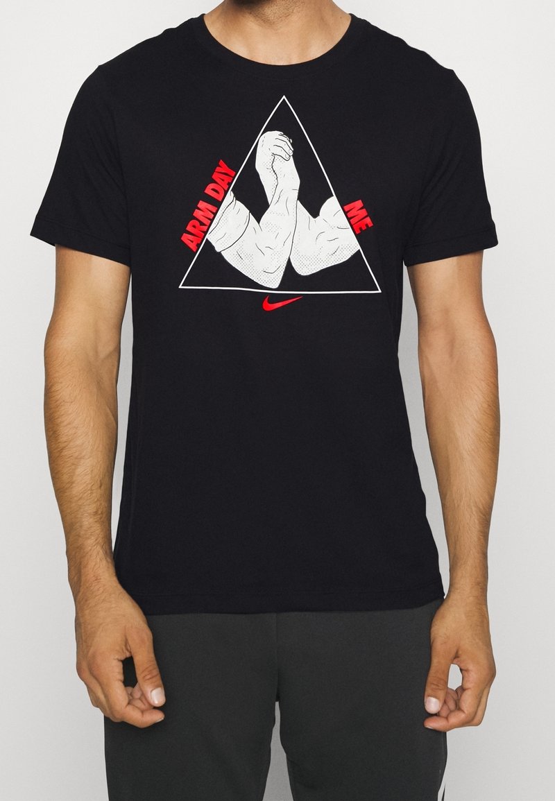 Camiseta de algodón negra con un gráfico en blanco y rojo de brazos flexionados dentro de un contorno triangular, con el texto “DÍA DE BRAZOS” y “YO.”