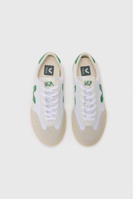 Hvit sneakers med grønne detaljer, laget av lær og kanvas, med perforerte detaljer, tradisjonelle snøringer, og en rund tåform.