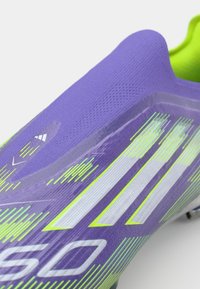 Lila Sportschuh mit strukturiertem Obermaterial, grünen Akzenten und weißen Details. Verfügt über ein schlankes Design und dynamische Streifen für optimale Leistung.