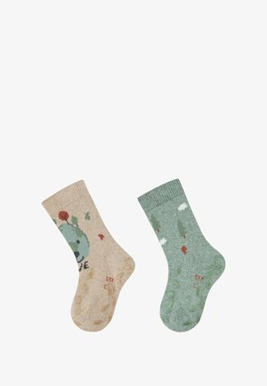 Zwei Paare gestrickte Socken; das eine beige mit einem grünen Design, das eine Figur und Blumen zeigt, das andere grün mit Mustern von Bäumen und Wolken.