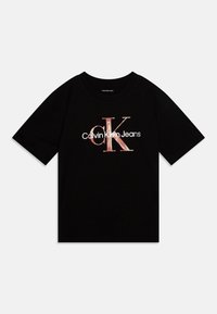 Camiseta de algodón negra con mangas cortas, que presenta un logo central en texto rosa y blanco: "Calvin Klein Jeans" y "CK" en una fuente estilizada.