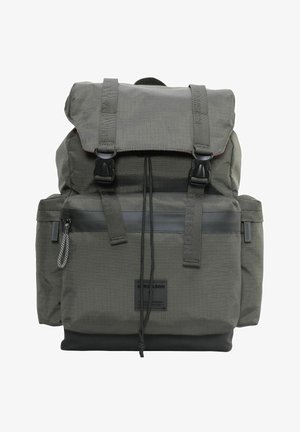 Sac à dos en tissu vert foncé avec des boucles noires, une poche zippée à l'avant, un système de fermeture à cordon et des poches latérales.