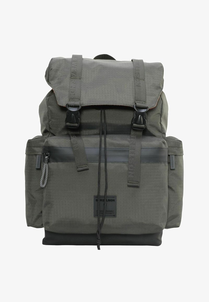 Mochila de tela verde oscuro con hebillas negras, un bolsillo frontal con cremallera, cierre de cuerda y bolsillos laterales.