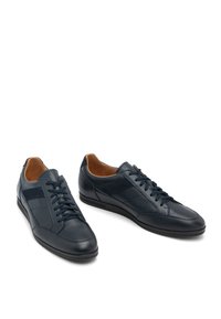 Námornícke kožené tenisky s textúrovaným povrchom, hladkými akcentmi a kontrastným hnedým interiérom. Šnurovací dizajn s gumovou podrážkou pre pohodlie.