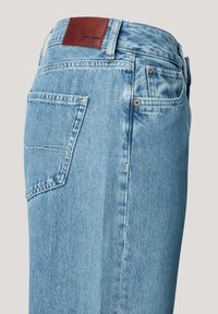 Ljust blå denimbyxor med midjehöjd, med en läderlabel baktill, en sidoficka och subtila blekningar på tyget.