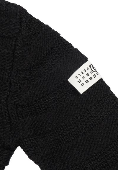 Maglione nero lavorato a maglia con un motivo a spina di pesce testurizzato. Un'etichetta bianca sulla manica mostra i numeri da 0 a 21.