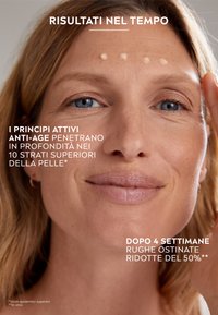 Primo piano del volto di una donna con pelle chiara e capelli lunghi, che mostra un incarnato uniforme e diversi punti di crema sulla fronte, su uno sfondo neutro.