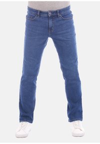Jeans in denim blu con taglio dritto, design a cinque tasche e dettagli di cucitura in evidenza, abbinati a sneakers bianche.