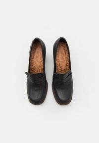 Černé kožené mokasíny s hladkým povrchem, zdobené zvýšeným švem a texturovanou stélkou. Zaoblená špička a nízká, polstrovaná podrážka.