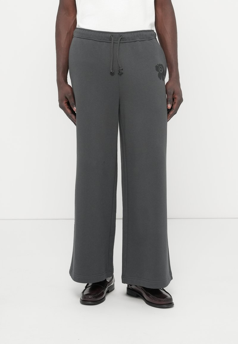 Γκρι φόρμες με άνετη εφαρμογή, ελαστική μέση με κορδόνι, πλαϊνές τσέπες και διακοσμητικό με λουλουδάτο σχέδιο στο αριστερό πόδι. Λείο, απαλό ύφασμα.