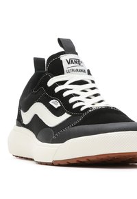 Le sneakers Vans Ultrastar in bianco e nero presentano una parte superiore nera texturizzata, dettagli del logo bianchi e una suola spessa di colore crema con un battistrada a motivi.
