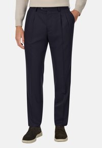 Jūras flotes stila bikses no gludas auduma, ar priekšējiem krokām, standarta jostasvietu un sānu kabatām. Valkātas ar tumšām kurpēm.