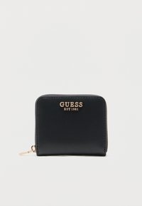 Cartera compacta negra con cierre de cremallera alrededor, con el logo dorado "GUESS EST 1981" y tirador de cremallera dorado sobre un fondo blanco.