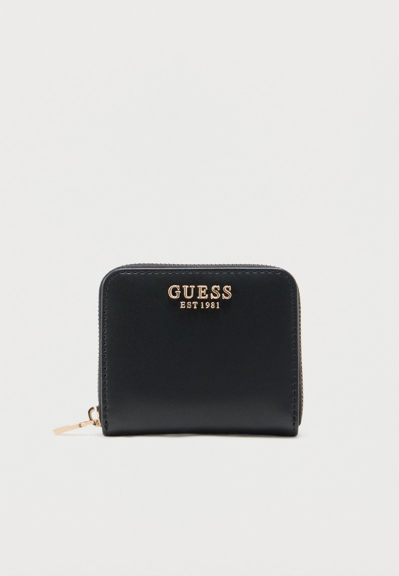 Cartera compacta negra con cierre de cremallera alrededor, con el logo dorado "GUESS EST 1981" y tirador de cremallera dorado sobre un fondo blanco.